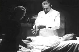 Capture from The Corpse Vanishes: Dr. George Lorenz (Bela Lugosi), in the Lab with Fagah (Minerva Urecal), Putting on Rubber Gloves