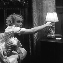 Square cropped capture from The House of Secrets (Roland D. Reed, 1936): Julie Kenmore (Muriel Evans) Turning on the Bedside Lamp